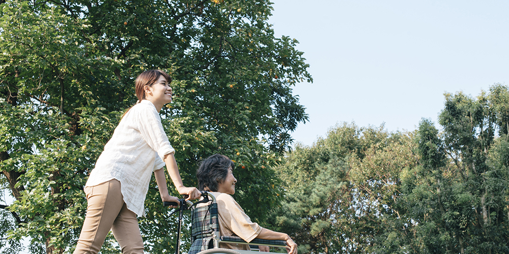 車椅子の女性と女性介護職員の散歩