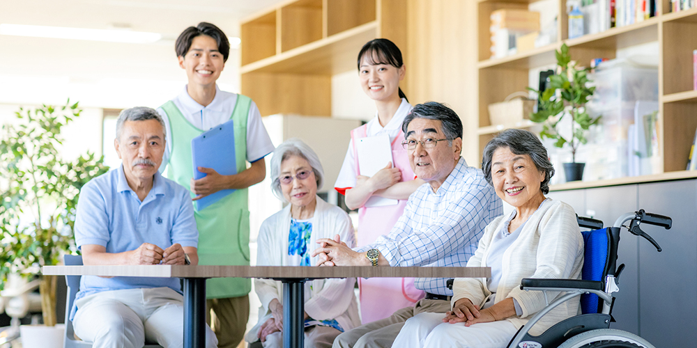 介護施設の共有スペースに集まる笑顔の高齢者たちと介護職員