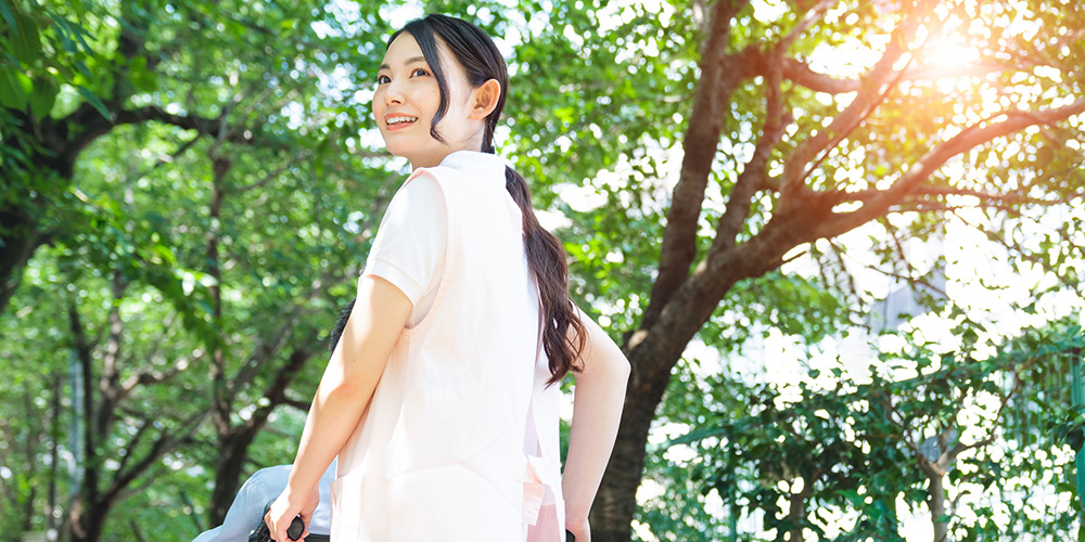 車椅子を押しながら振り向く女性介護職員