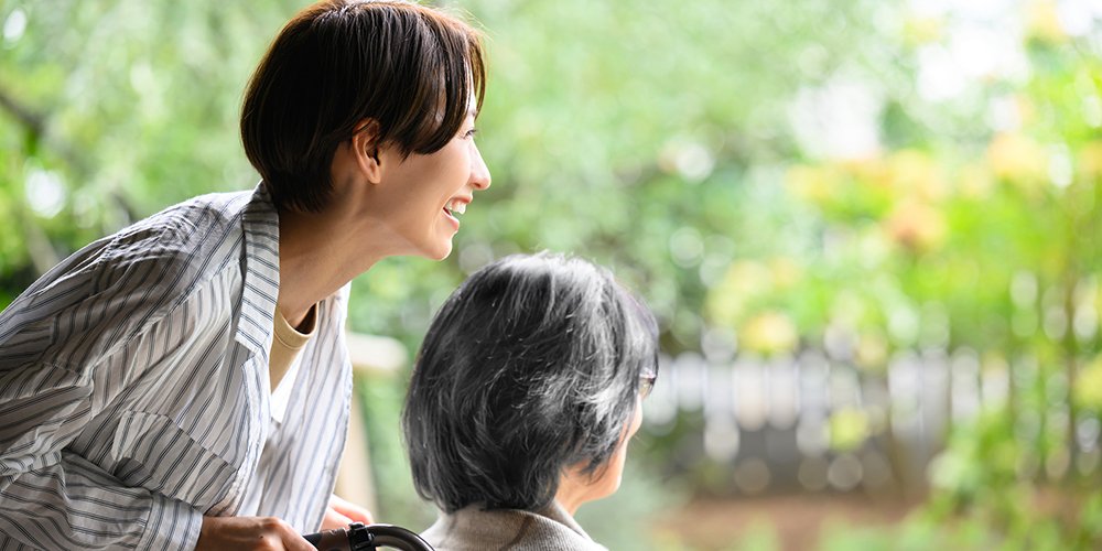 外を眺める車椅子の女性と車椅子を押す女性